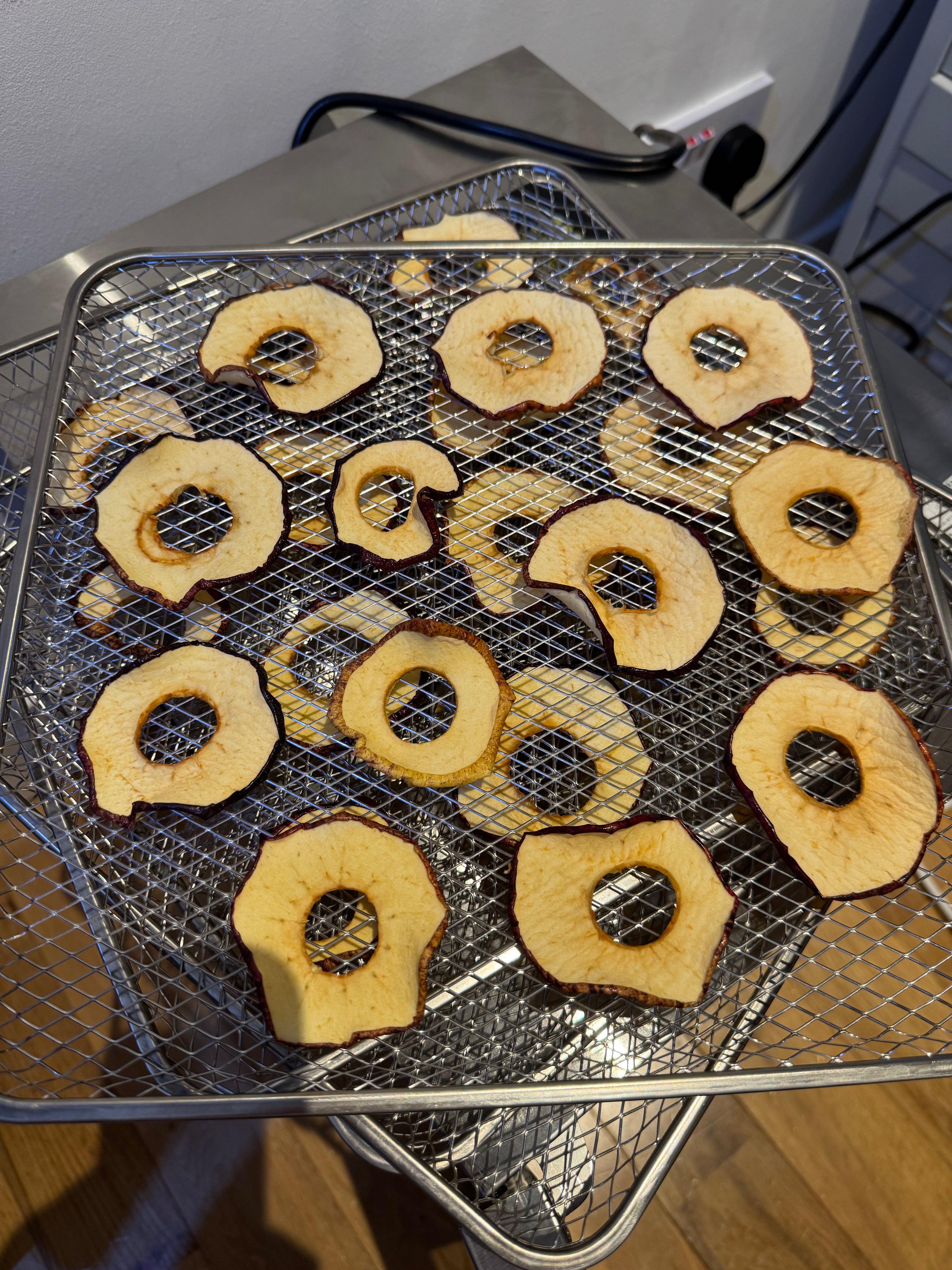 Apple slices dehydrating on a wire rack during the apple crisps drying process